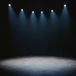an empty stage illuminated by three lights in front of it