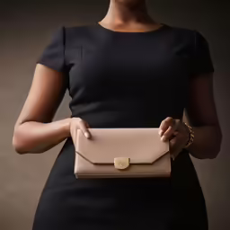 a women in black is holding a tan purse