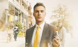 a young man in a suit holding something up to his face