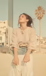 a woman sitting in the sand next to palm trees