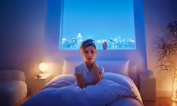 a person sitting on a bed with a lamp in the corner