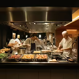 two chefs making pizzas in a kitchen