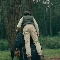 a person in brown jacket carrying onto tree
