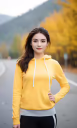 the young woman wearing a yellow hoodie stands on the street