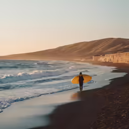 a person carrying a surfboard on top of a beach