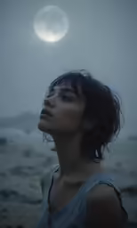 a woman staring upward into the sky on a beach