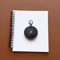 a spiral notebook next to a black pendant