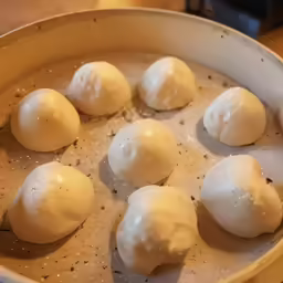 a pan with eight doughnuts and one being mixed