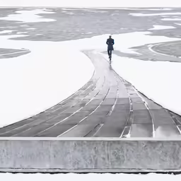 a man walking down a pathway next to a body of water