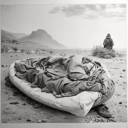 a man in a desert setting kneeling over a sleeping bag