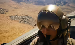 a young boy wearing goggles is in an airplane with open wings