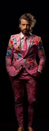 a man dressed in a floral suit, shoes, and sandals,a man in pink suit standing on a black background