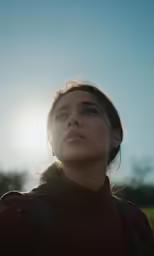 a woman with short hair looking up at the sun