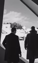 two men are walking up an escalator looking down at the city