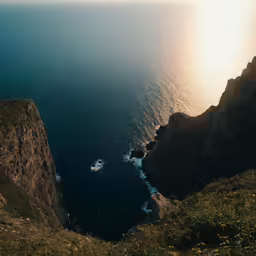a man and woman looking out at the water from a cliff