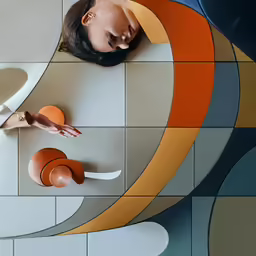 a woman laying down on a floor made with colorful tiles