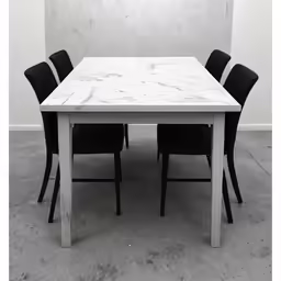 an empty table and black chairs against a wall